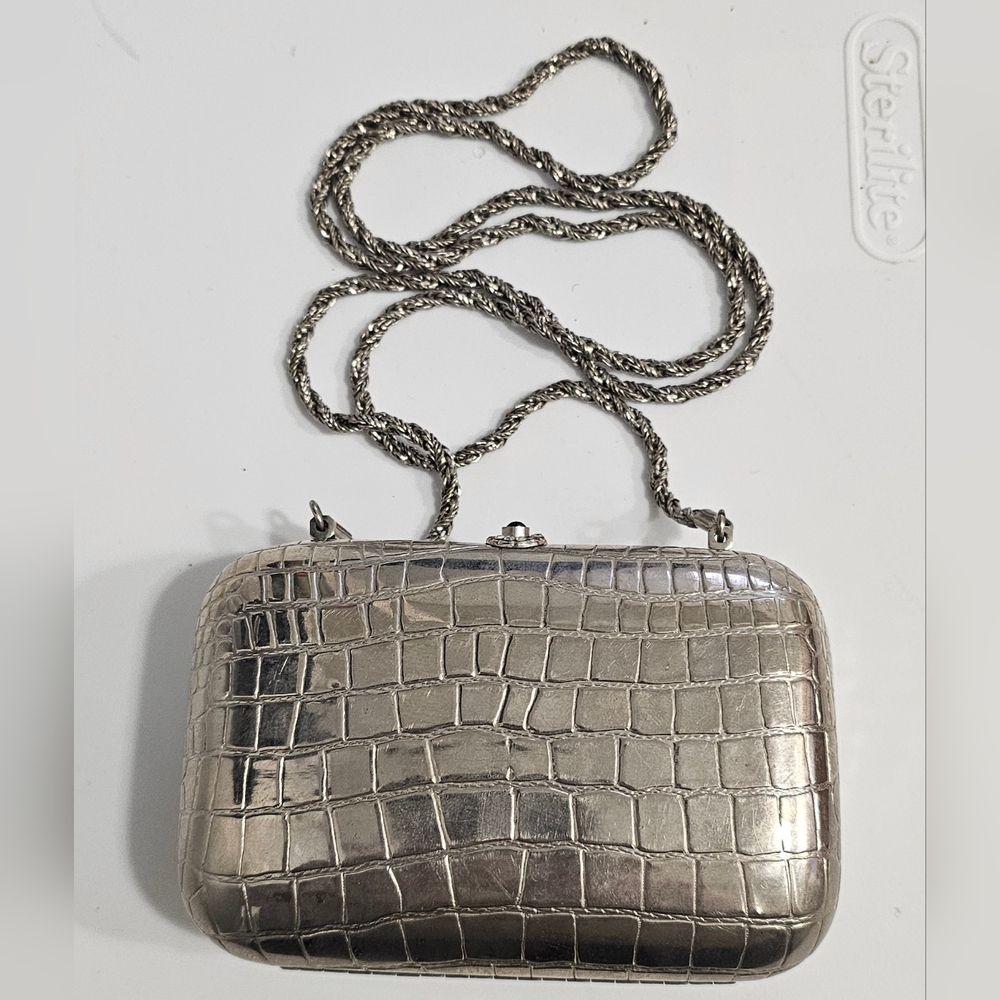 Made in Italy. Silver tone metal with crocodile embossed. Hard case.